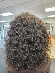 A 12-inch natural black curly wig displayed on a mannequin head, featuring a realistic hairstyle with a flat surface.